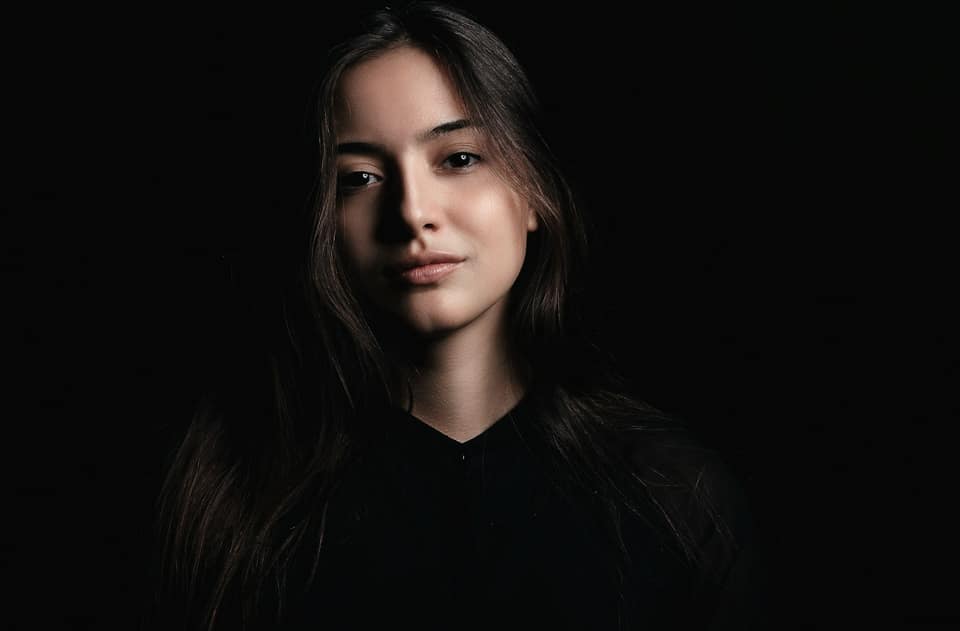 Portret van een vrouw met donker haar tegen een donkere achtergrond